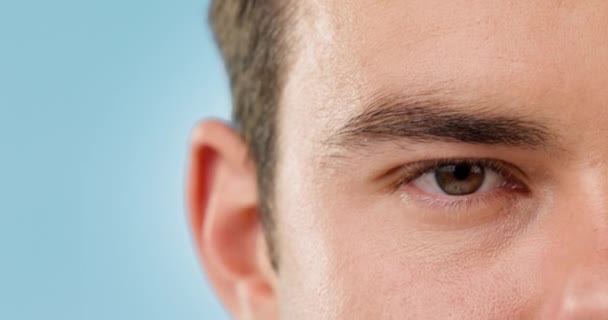 Closeup, eye and man with vision, health and optometry with retina on a blue studio background. Mockup space, person and model with wellness, aesthetic and beauty with clear sight, looking and see. - Footage, Video