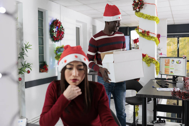Un employé afro-américain emménage dans un nouveau bureau décoré pour Noël après avoir accepté un nouveau poste dans l'entreprise. Travailleur excité de commencer un nouvel emploi dans un espace de travail décoré et festif - Photo, image