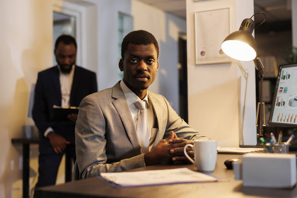 Африканський американський працівник, який працює за стратегією компанії, аналізує документи з фінансовою статистикою в стартап-офісі. Виконавчий менеджер мозковий штурм бізнес-ідеї, намагаючись збільшити прибуток - Фото, зображення