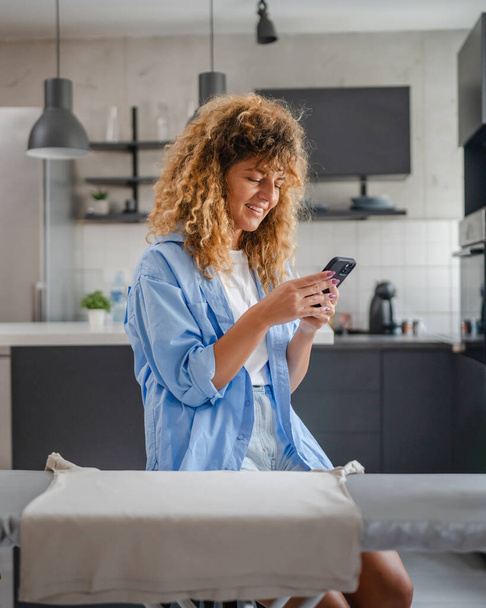 Dorosła kobieta korzysta z aplikacji telefon komórkowy aplikacji otrzymywać powiadomienia e-mail sms w domu bankowości online lub dobre wieści szczęśliwy uśmiech - Zdjęcie, obraz