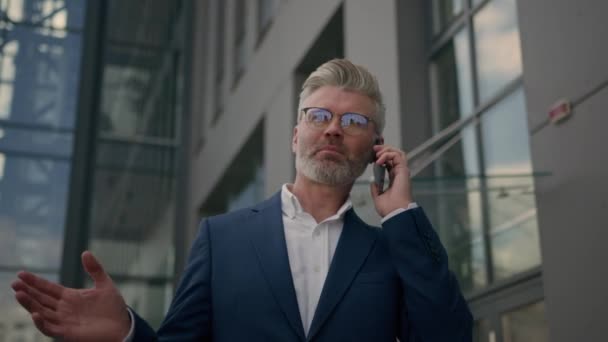 Komoly séta középkorú vezető kaukázusi üzletember közel cég irodaház felhőkarcoló vezérigazgató alkalmazott érett férfi üzletember talk call séta a városban szabadban vállalkozó beszél mobiltelefon - Felvétel, videó
