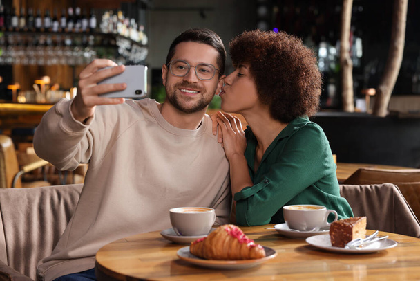 International dating. Happy couple taking selfie in cafe - Fotó, kép
