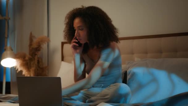 Rozzlobený africký americký žena businesswoman pracuje na domácí posteli s notebookem papíry šílený mluvit mobilní telefon konflikt stresu dívka pozdě v noci přepracování problém s dokumenty smartphone křičí hádky - Záběry, video