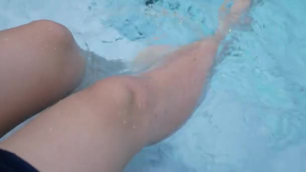 Primo piano di gambe femminili sottili contro l'acqua limpida blu vicino alla piscina rilassante vacanza nella calda giornata estiva sotto il sole.gambe nell'acqua della piscina, riposo, prendere il sole. - Filmati, video