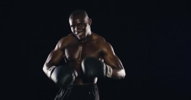 Gezicht, klaar of zelfverzekerd bokser in studio met kracht voor fitness of wellness op zwarte achtergrond. Vechten, Afrikaanse vechter of vrolijke man in bokshandschoenen voor training, gevechtstraining of mma-oefening. - Video