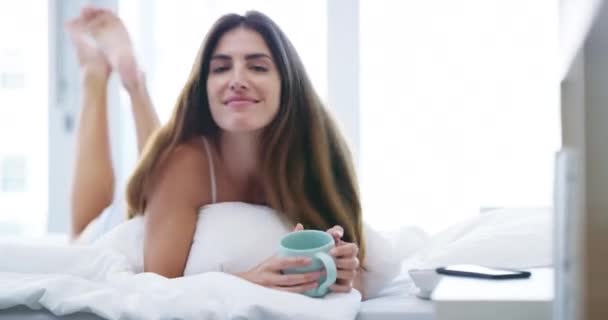 Gesicht, Lächeln und Frau mit Kaffeetasse im Schlafzimmer zu Hause, entspannen und gesundes Frühstück, trinken Latte und Espresso. Porträt eines glücklichen Menschen mit Teetasse morgens im Bett, liegend und wach im Haus. - Filmmaterial, Video