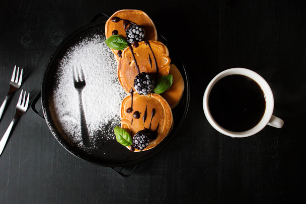 pannenkoeken met chocolade en frambozen.Pannenkoeken met bessen op een zwarte houten achtergrond. dessert. ontbijt. - Foto, afbeelding