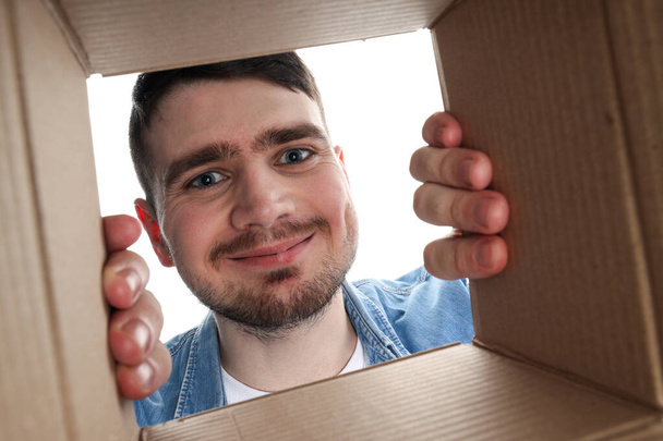 PNG, Młody atrakcyjny facet patrzy w kartonowe pudełko, odizolowane na białym tle - Zdjęcie, obraz