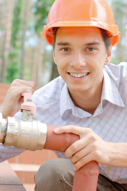 Lächelnder Arbeiter, der ein Rohr repariert - Foto, Bild