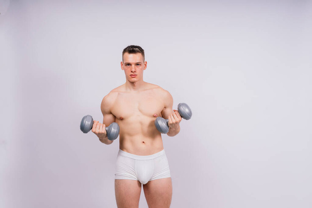 Shirtless bodybuilder holding a dumbell and showing his muscular arms. - Valokuva, kuva