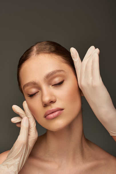 estetiste in guanti medici toccare il viso della donna su sfondo grigio, concetto di dermatologia - Foto, immagini