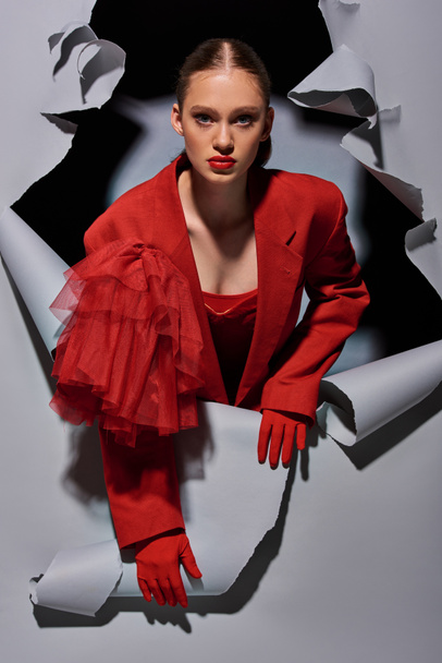 trendikäs nuori nainen punaisessa puvussa rohkea meikki murtaa harmaa tausta reikä - Valokuva, kuva