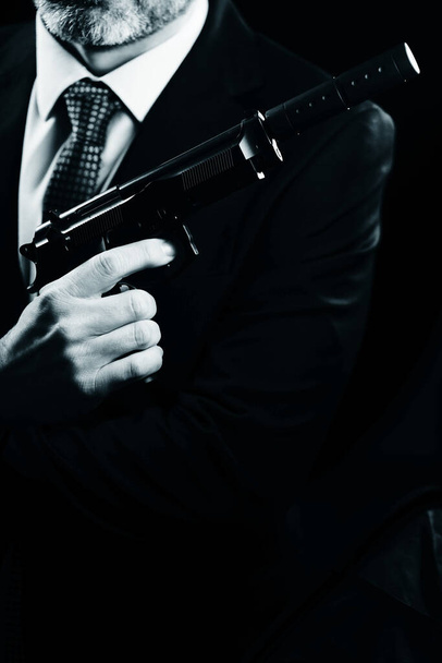 Hombre bien vestido agente secreto detective espía usando traje y corbata sosteniendo pistola automática. - Foto, Imagen
