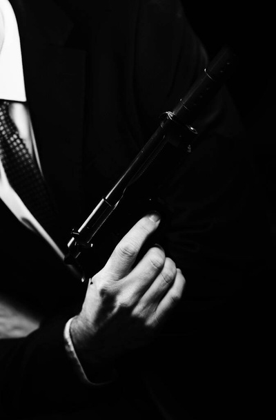 Goed geklede mannelijke geheim agent detective spion draagt pak en stropdas met automatisch pistool. - Foto, afbeelding