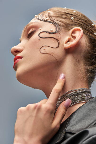 Nahaufnahme des schönen jungen Modells mit trendigen Perlstiften im Haar und roten Lippen vor grauem Hintergrund - Foto, Bild