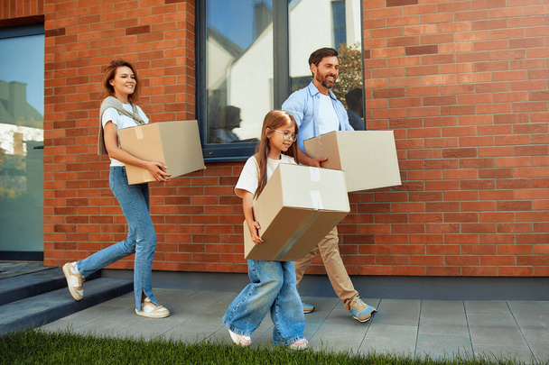 A young family with two children daughters carry boxes of things into the car. Renting and buying a home. Moving to a new home. - Photo, Image