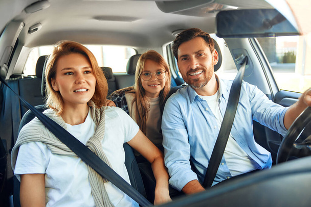 Eine Familie mit Tochter und hübschem Kind sitzt im Auto und fährt für ein Wochenende in den Urlaub. Konzept für Erholung, Tourismus und Reisen. - Foto, Bild