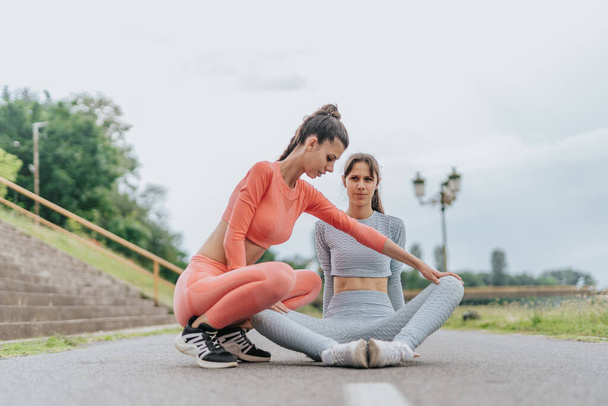 Sportler betreiben in einem Stadtpark eine Fitness-Routine. Zwei fitte Weibchen demonstrieren ihre Körperveränderung, indem sie mit Freunden Ausdauer- und Dehnübungen machen. - Foto, Bild