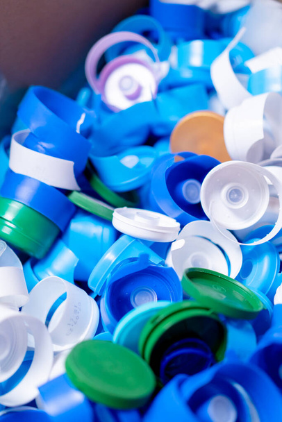 Imagem de close-up de tampas multicoloridas de garrafas usadas armazenadas em uma estação de reciclagem e triagem de resíduos - Foto, Imagem