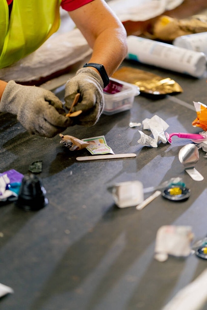 Primer plano de las manos femeninas en guantes de trabajo clasificando la basura en categorías en una línea especial en una fábrica - Foto, imagen