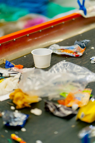 Un primer plano de plástico usado y basura de papel se encuentra en la línea de clasificación de una estación de reciclaje de residuos - Foto, imagen