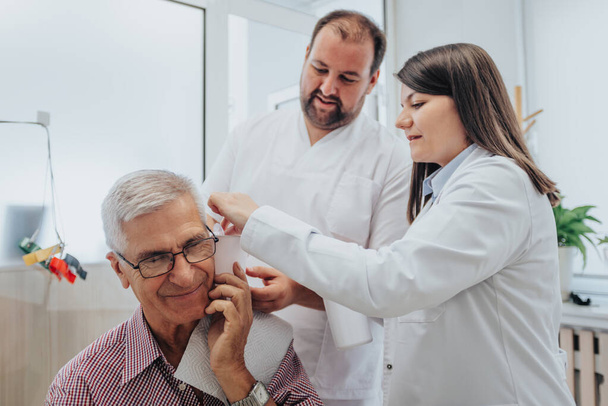 Experienced doctors conducting thorough health exams in a clinical setting, checking eyesight, hearing, and throat. Professional care for patients of all ages. - Photo, Image