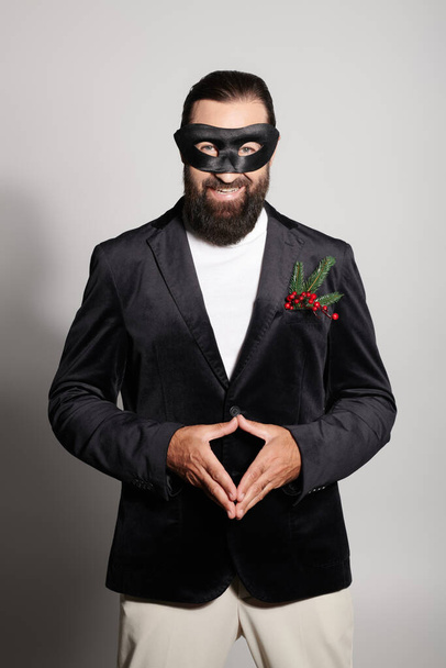 Maskerade bal, vrolijke man met baard in carnaval masker en elegante formele slijtage op grijze achtergrond - Foto, afbeelding