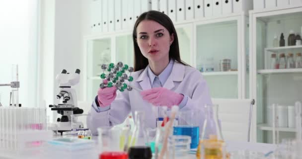 Laboratório químico estuda a estrutura de moléculas em plástico modelo 3D. Estudante e estrutura molecular feminina em laboratório - Filmagem, Vídeo