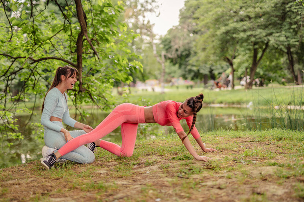 Ενεργό, κατάλληλα κορίτσια τεντώσει, άσκηση, και να εκπαιδεύσει σε εξωτερικούς χώρους σε ένα πάρκο της πόλης, επιδεικνύοντας την αφοσίωσή και την ενέργειά τους. - Φωτογραφία, εικόνα
