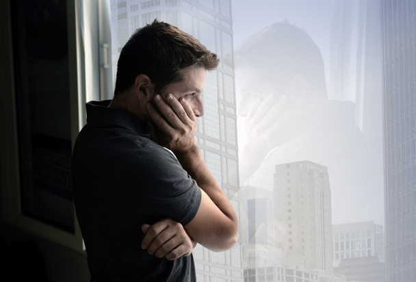 homem atraente olhando através da janela sofrendo crise emocional e depressão
 - Foto, Imagem