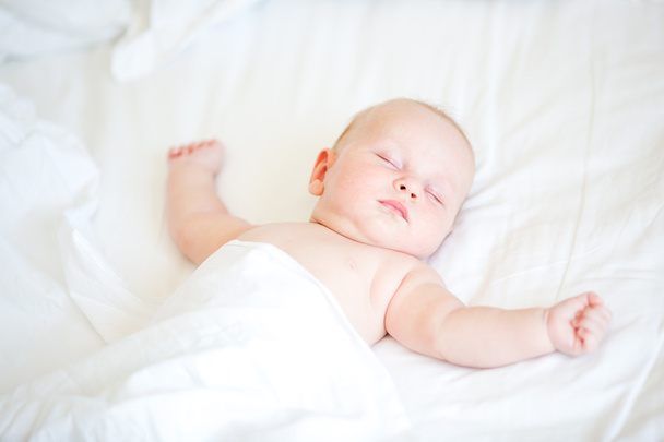 Peaceful newborn baby lying on a bed sleeping - Fotó, kép