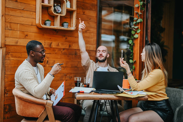 Jonge leidinggevenden en ondernemers ontmoeten elkaar in een stedelijke koffiebar om te chatten over expansie, ROI, risico-evaluatie, strategie en trends, het bundelen van hun middelen om een succesvolle startup te maken. - Foto, afbeelding