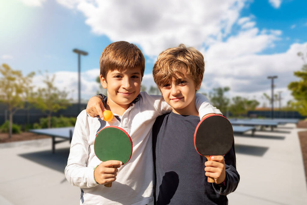 Dvě děti s ping pong pádla hrát na venkovních sportovištích. Sportovní umění v mládí. mimoškolní aktivity pro děti - Fotografie, Obrázek