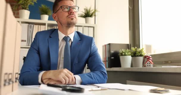 Nachdenklicher Geschäftsmann mit Brille sitzt am Arbeitsplatz. Neue Ideen für Geschäftskonzept finden - Filmmaterial, Video