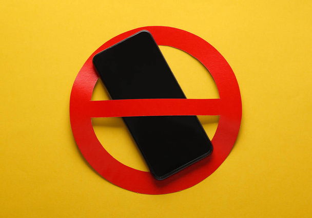 Smartphone with red prohibition sign on yellow background. Ban - Photo, Image