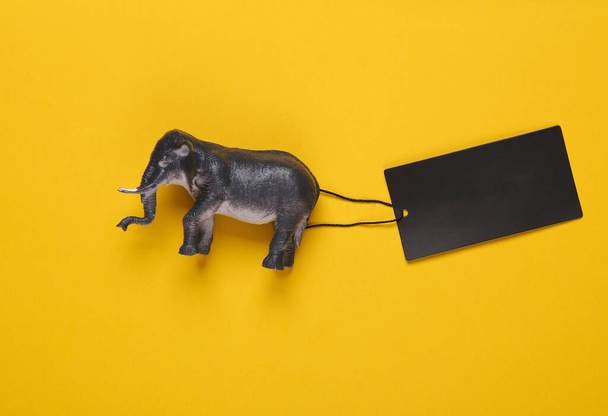 Elefante giocattolo con cartellino del prezzo su sfondo giallo. Vendita, concetto di shopping - Foto, immagini