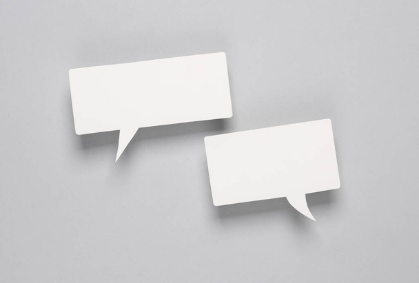 Witte blanco papier gesneden spraakbellen op grijze achtergrond. Chat, sociale media, discussie. Mock up voor template ontwerp - Foto, afbeelding
