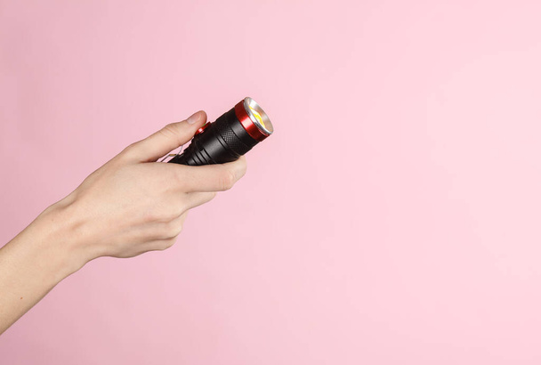 Female hand holding a flashlight on a pink background - Photo, Image