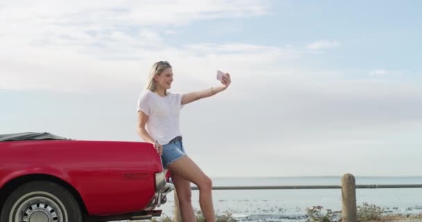 Woman, selfie and car for road trip by beach for wellness, vacation or holiday in Australia. Young person, laugh and picture for memory, travel or social media for post of adventure, ocean and summer. - Footage, Video