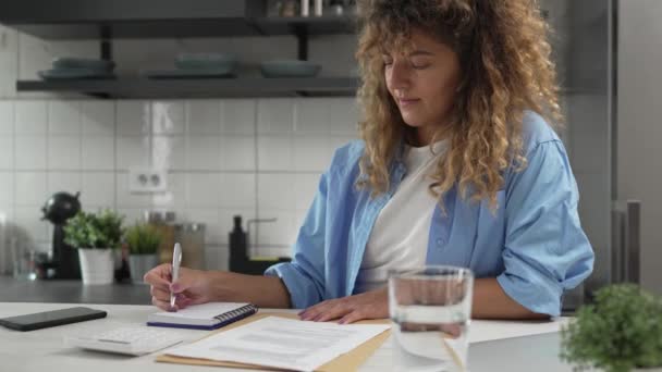 Mujer caucásica en la calculadora de uso doméstico para calcular gastos e impuestos - Imágenes, Vídeo