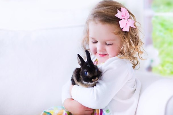 Petite fille jouant avec un lapin
 - Photo, image