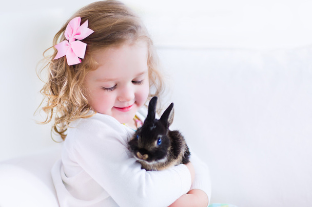 Little girl playing with a rabbit - Фото, зображення