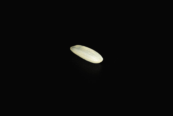 Κοντινό πλάνο άψητων κόκκων ρυζιού σε μαύρο φόντο. Έννοια υγιεινής διατροφής - Φωτογραφία, εικόνα