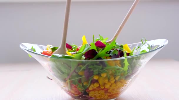 wooden spoons stir salad in glass plate corn tomatoes cucumbers bulgarian yellow peppers arugula leaves vegetarian food lunch slimming diet close-up female hands - Footage, Video