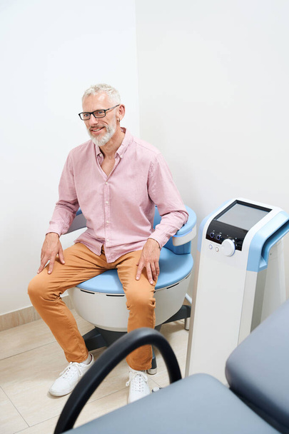 Homem velho barbudo submetido a fisioterapia em uma instalação médica moderna, a clínica tem equipamentos eficientes - Foto, Imagem