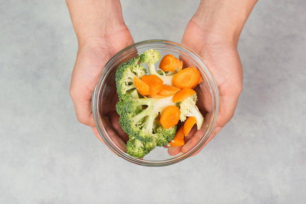 Trzymając świeże organiczne brokuły i marchewki w dłoni, przygotować zdrową żywność z warzyw, zbiorów i rolnictwa - Zdjęcie, obraz