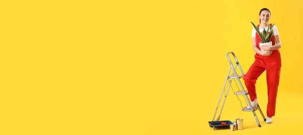 Νεαρή γυναίκα με φυτό εσωτερικού χώρου, σκάλα και μπογιές σε κίτρινο φόντο με χώρο για κείμενο - Φωτογραφία, εικόνα