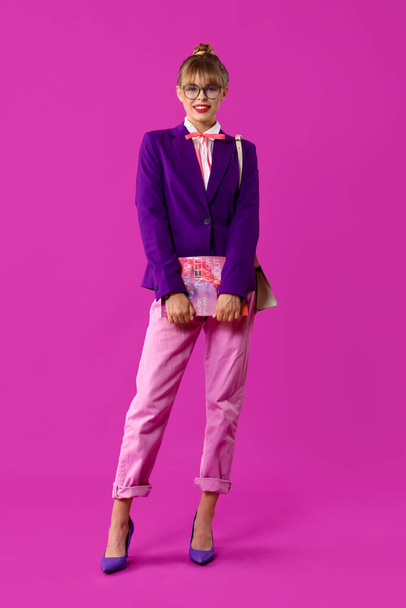 Młoda kobieta ubrana jak lalka z magazynem na fioletowym tle - Zdjęcie, obraz