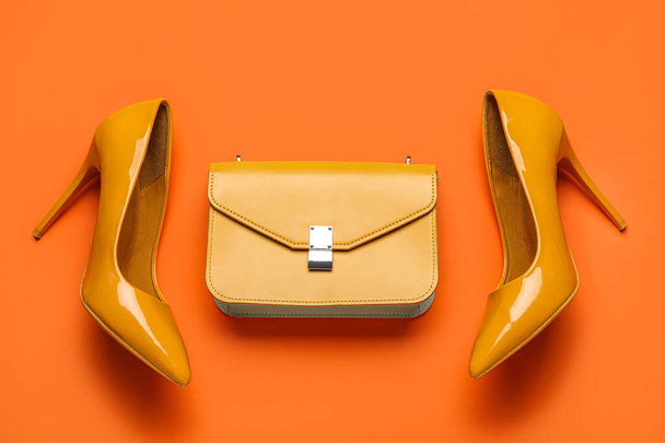 Stijlvol geel hoge hakken en portemonnee op oranje achtergrond - Foto, afbeelding