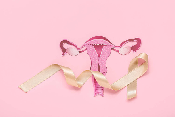 Papieren baarmoeder met beige lint op roze achtergrond. Begrip kankerbewustzijn - Foto, afbeelding